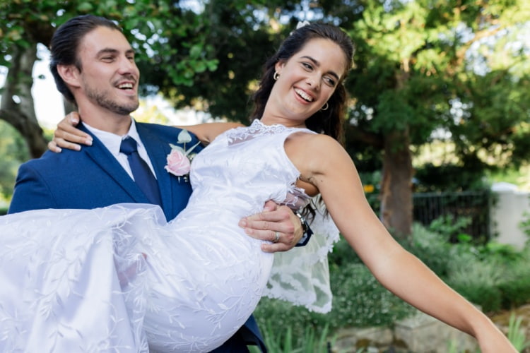 Groom holding bride after garden wedding ceremony